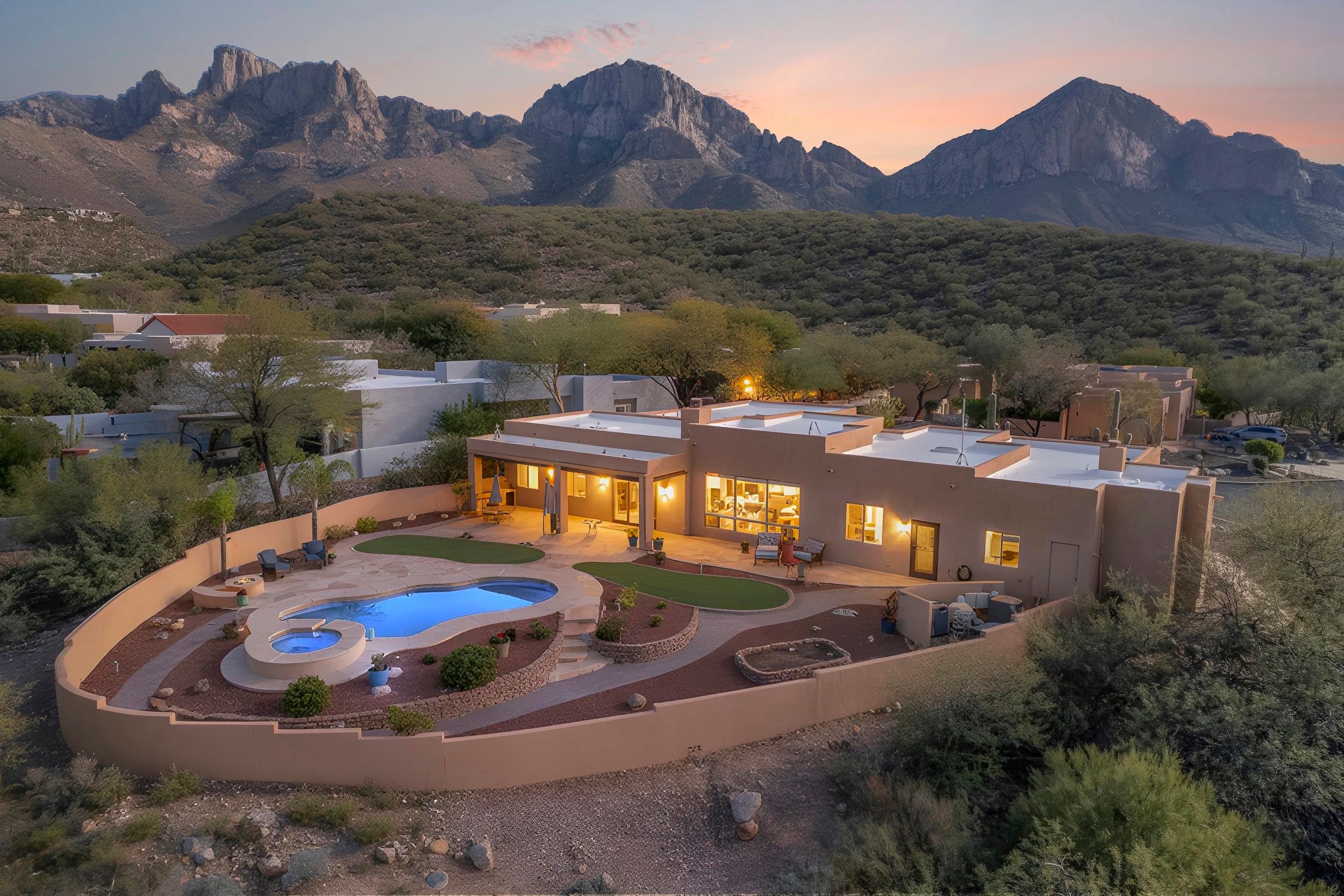 An adobe home and pool at twilight beneath the Santa Catalina Mountains